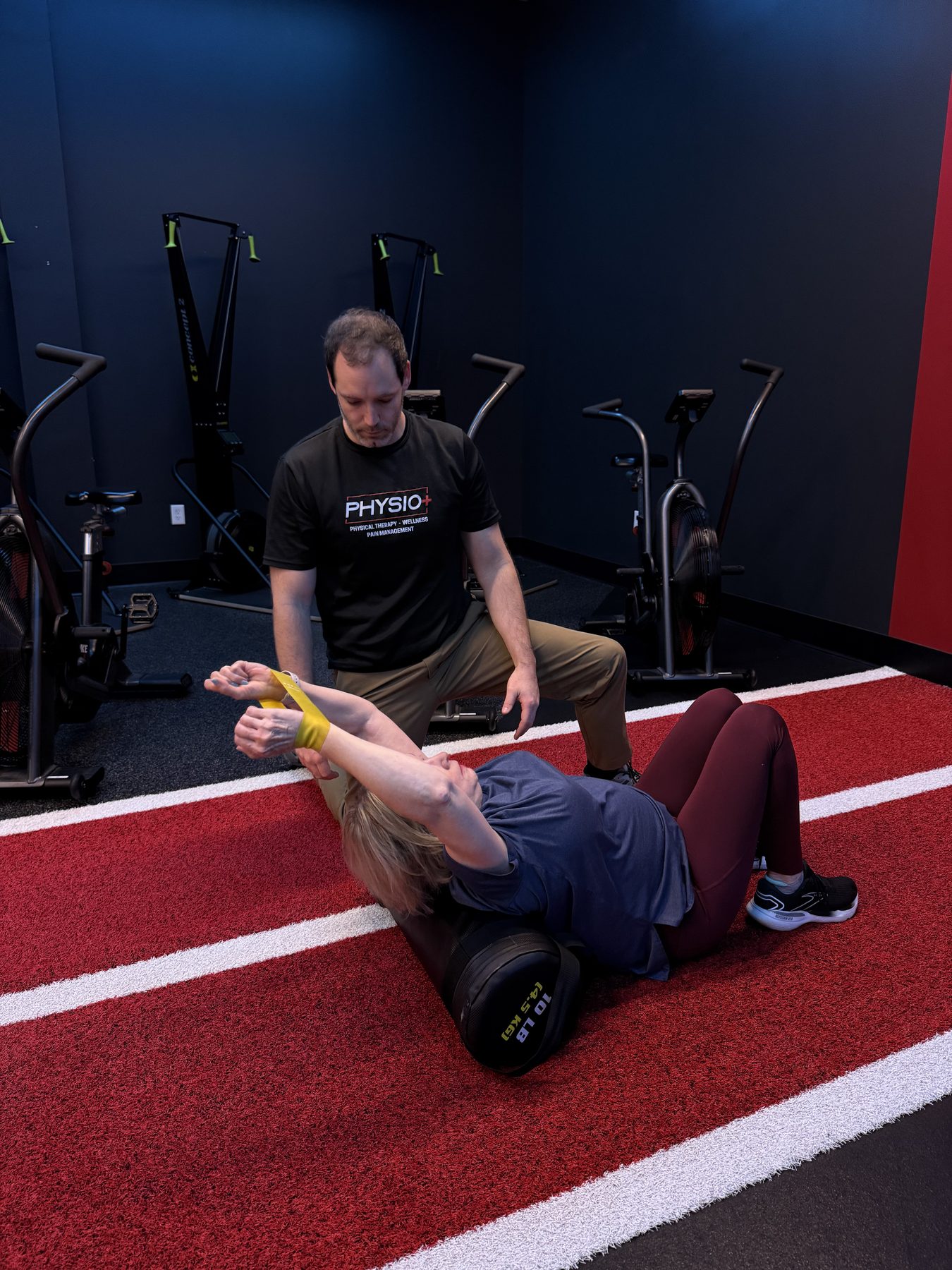 Physio+ provider taping an athlete's ankle on the indoor track