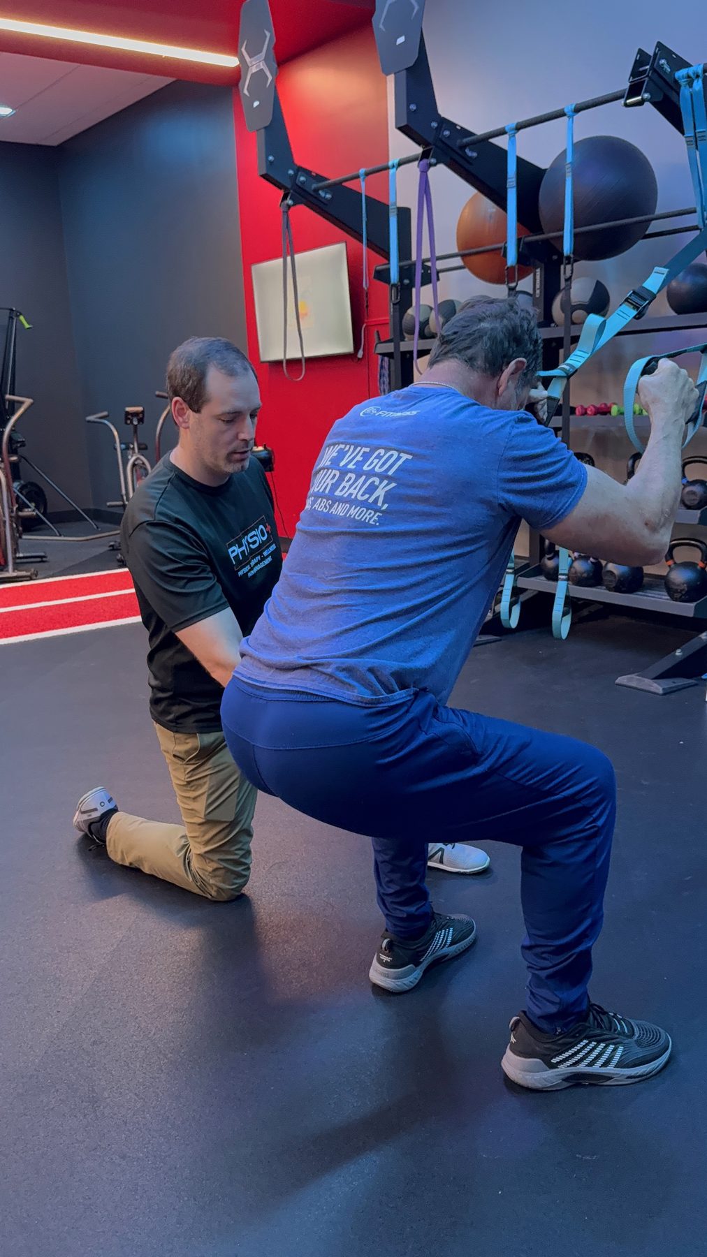Physio+ provider coaching a patient through a loaded squat pattern