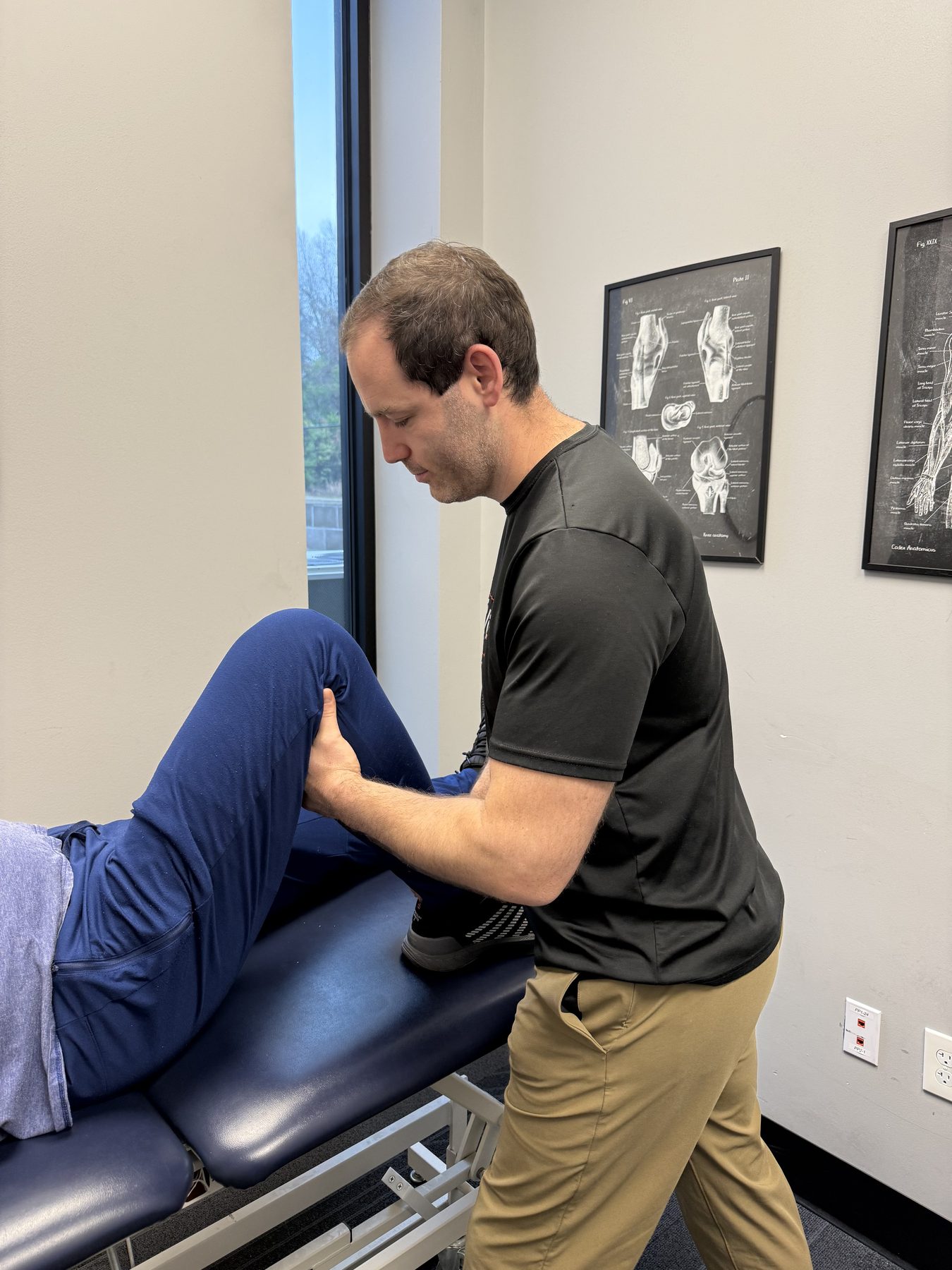 Private exam room at Physio+ with anatomy reference charts